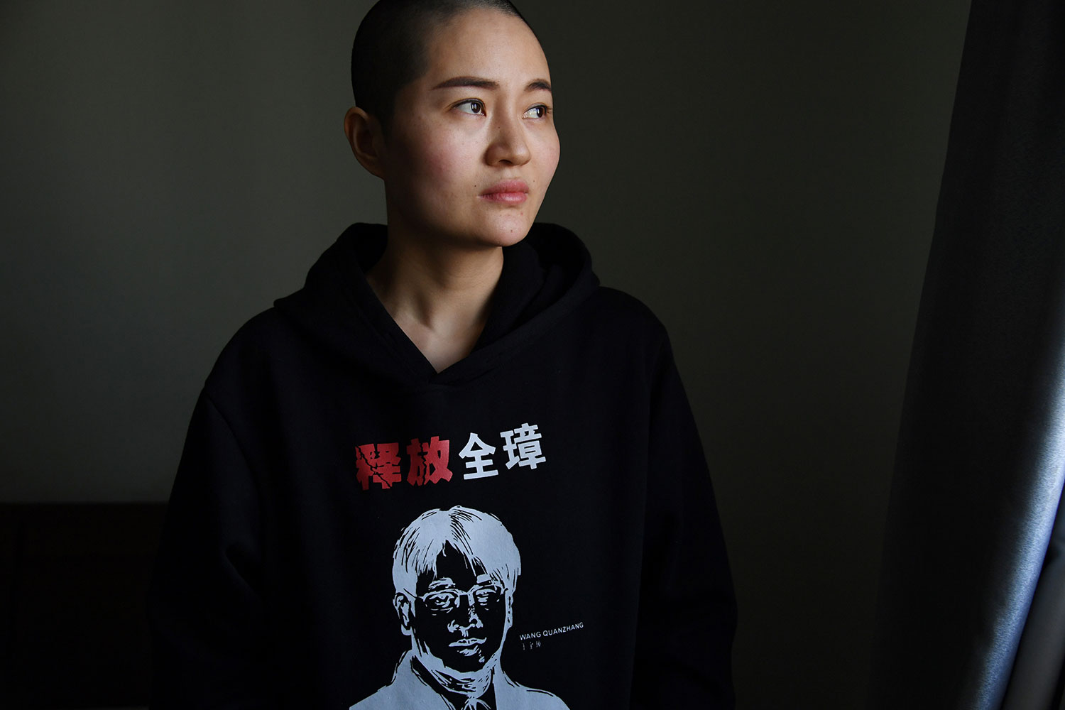 资料图片：2019年1月28日，中国人权律师王全璋的妻子李文足在北京的家中，穿着一件带有丈夫肖像的衣服，印有“释放全璋”的字样。（AFP）