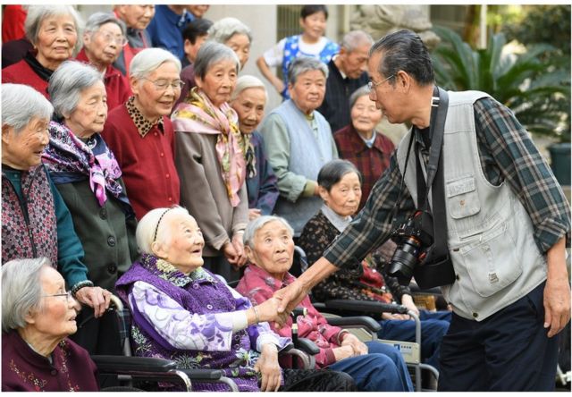 86岁的老年摄影爱好者谢金声为湖州社区里老年公寓的老人拍合影