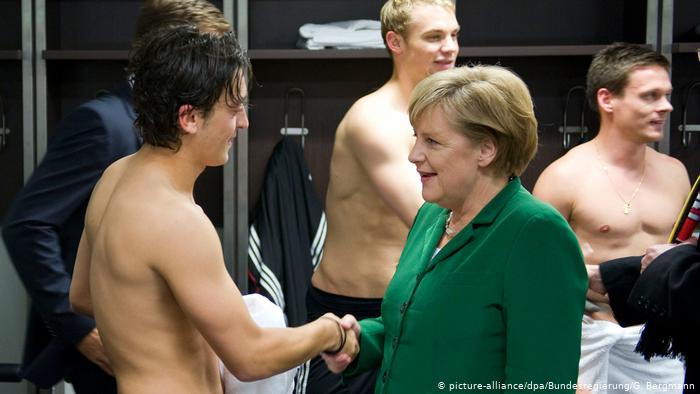 Mesut Özil meets Angela Merkel in a football changing room in 2010 (picture-alliance/dpa/Bundesregierung/G. Bergmann)