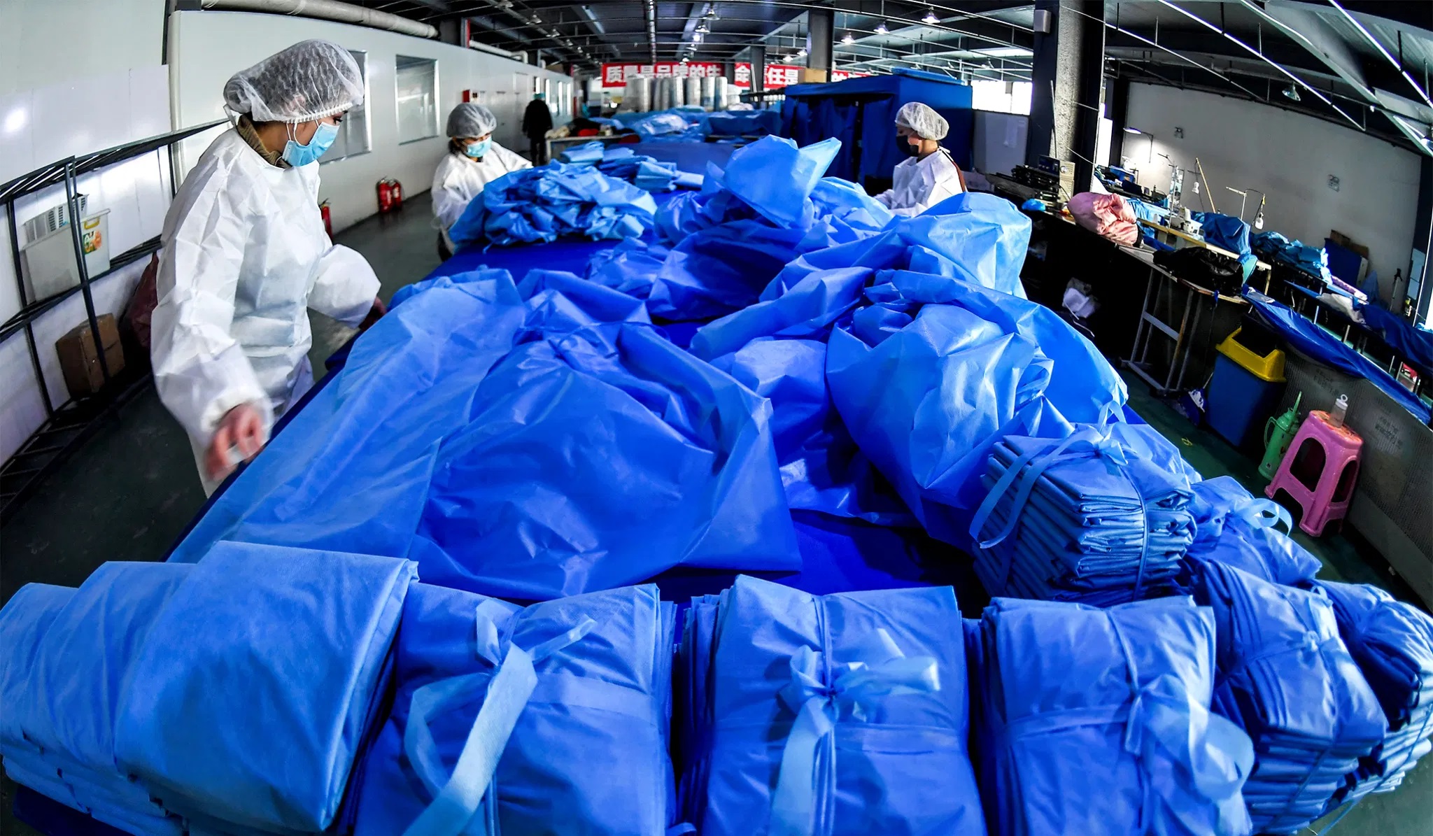 资料图片：2020年1月27日，在中国新疆维吾尔自治区乌鲁木齐市一家医疗设备制造商的工厂里，工人在生产防护服和口罩的生产线上劳动。（路透社）