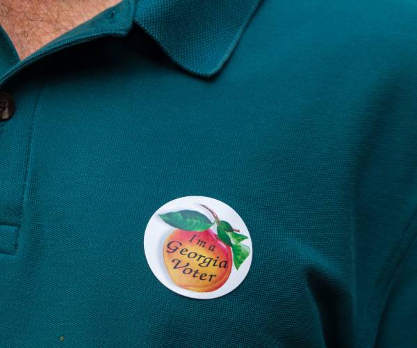 a person wearing an i voted sticker with a georgia peach on it